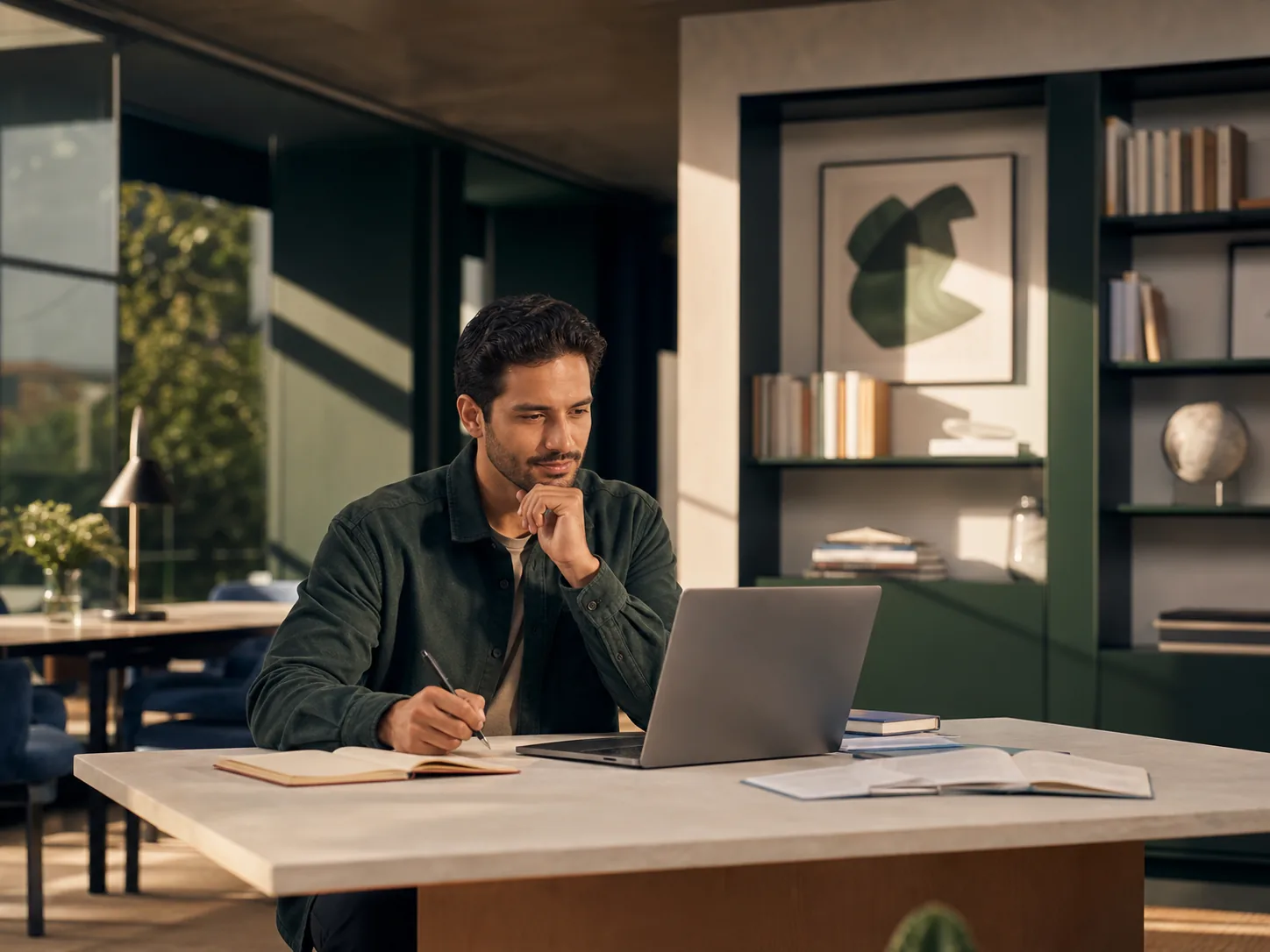 An adult learner researching at a laptop in a calm green and ivory study space.